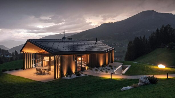 A modern house with a dining area, kitchen, and a large window overlooking a mountainous landscape.