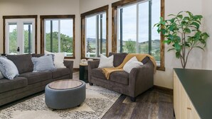 A living room with two sofas, a coffee table, and a large window with a view of the outdoors. - Lava`s Red King of The Hill (Lava Hot Springs)