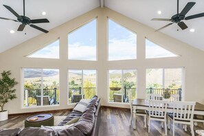 A spacious living room with a high ceiling, large windows, and a view of the countryside. - Lava`s Red King of The Hill (Lava Hot Springs)