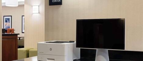Un centro de negocios con una impresora, un monitor y un teclado sobre un mostrador.