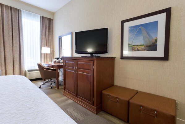A hotel room with a bed, a desk, a television, a wardrobe, and a suitcase. - Wingate by Wyndham St. Louis Airport (St. Ann)