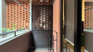 En smal gang med træloft, gelænder i metal og en mur med et gittermønster.
