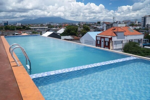 A rooftop swimming pool with a clear view of the cityscape and mountains in the background. - Liberta Malioboro North (Gedong Tengen)