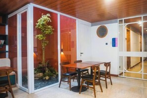 Quarto com uma mesa de jantar e cadeiras, uma pequena planta dentro de casa e teto de madeira.
