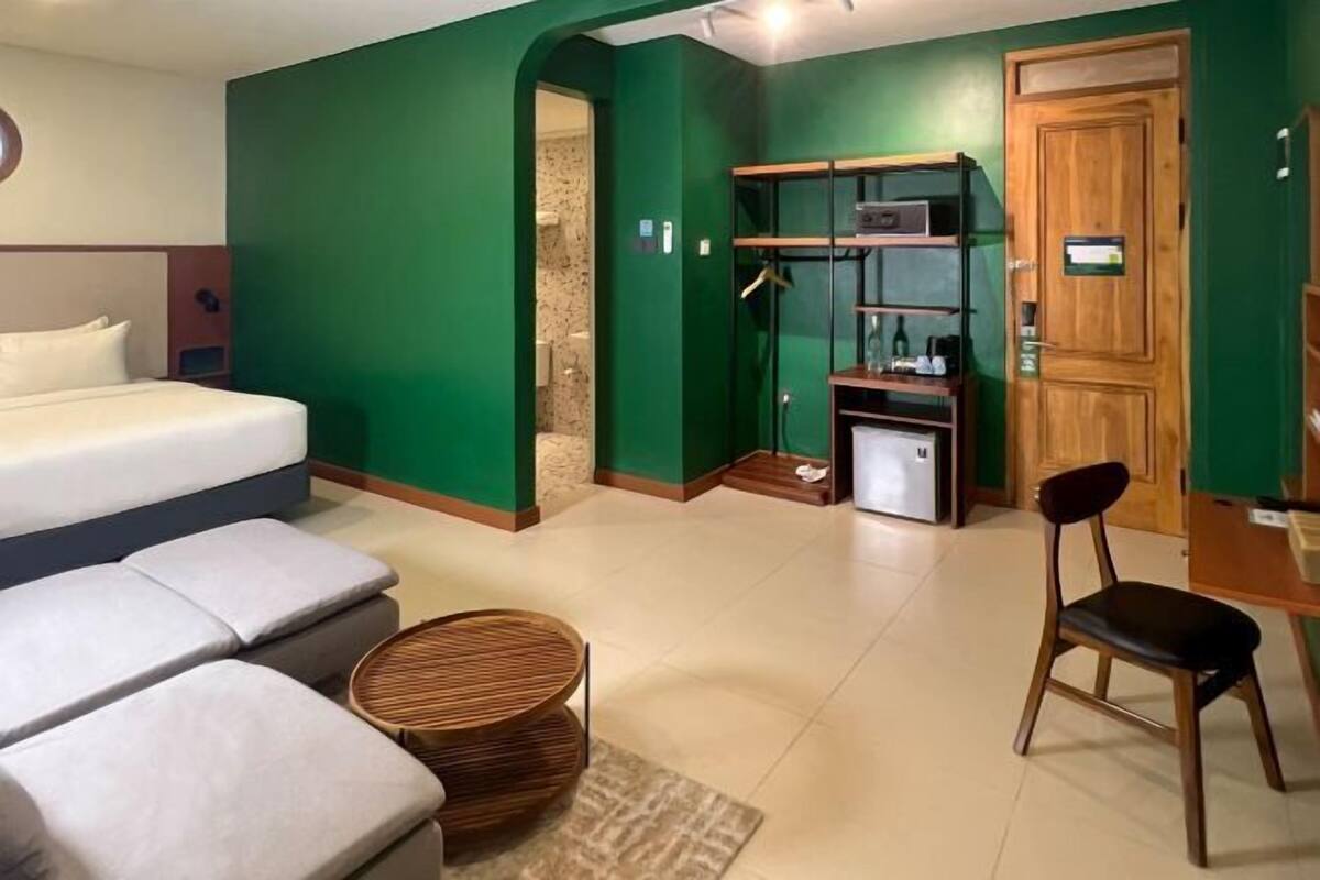 Une pièce comprenant un lit, un canapé, une chaise, une petite table et une étagère avec divers objets.