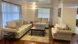 A living room with a sectional sofa, a small table, and a coffee table. - Spacious 4-bedroom villa with a Pool in serene Athiriver BAOB (Athi River)
