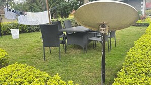 An outdoor patio with a dining table and chairs, a satellite dish, and a clothesline with laundry. - Spacious 4-bedroom villa with a Pool in serene Athiriver BAOB (Athi River)