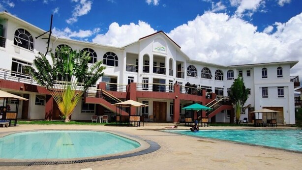 A hotel with a swimming pool, multiple balconies, and a central courtyard. - Spacious 4-bedroom villa with a Pool in serene Athiriver BAOB (Athi River)