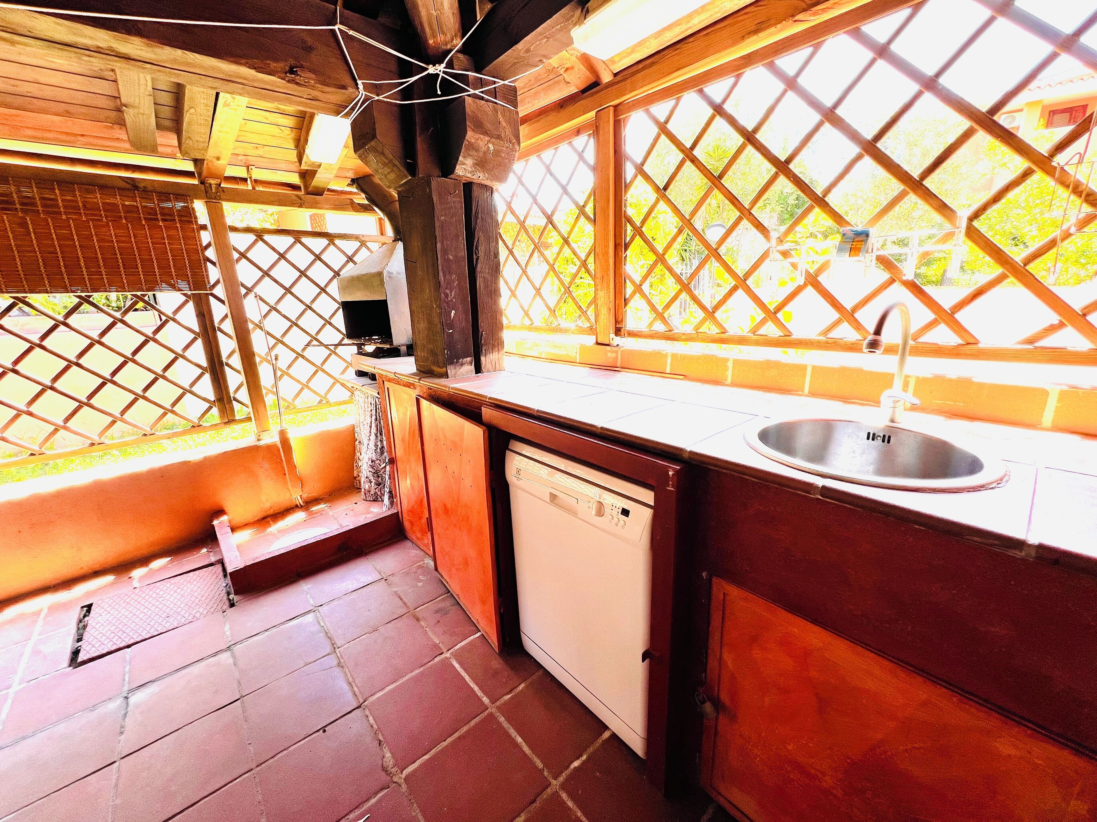 A compact kitchen with a sink, dishwasher, and wooden cabinets.