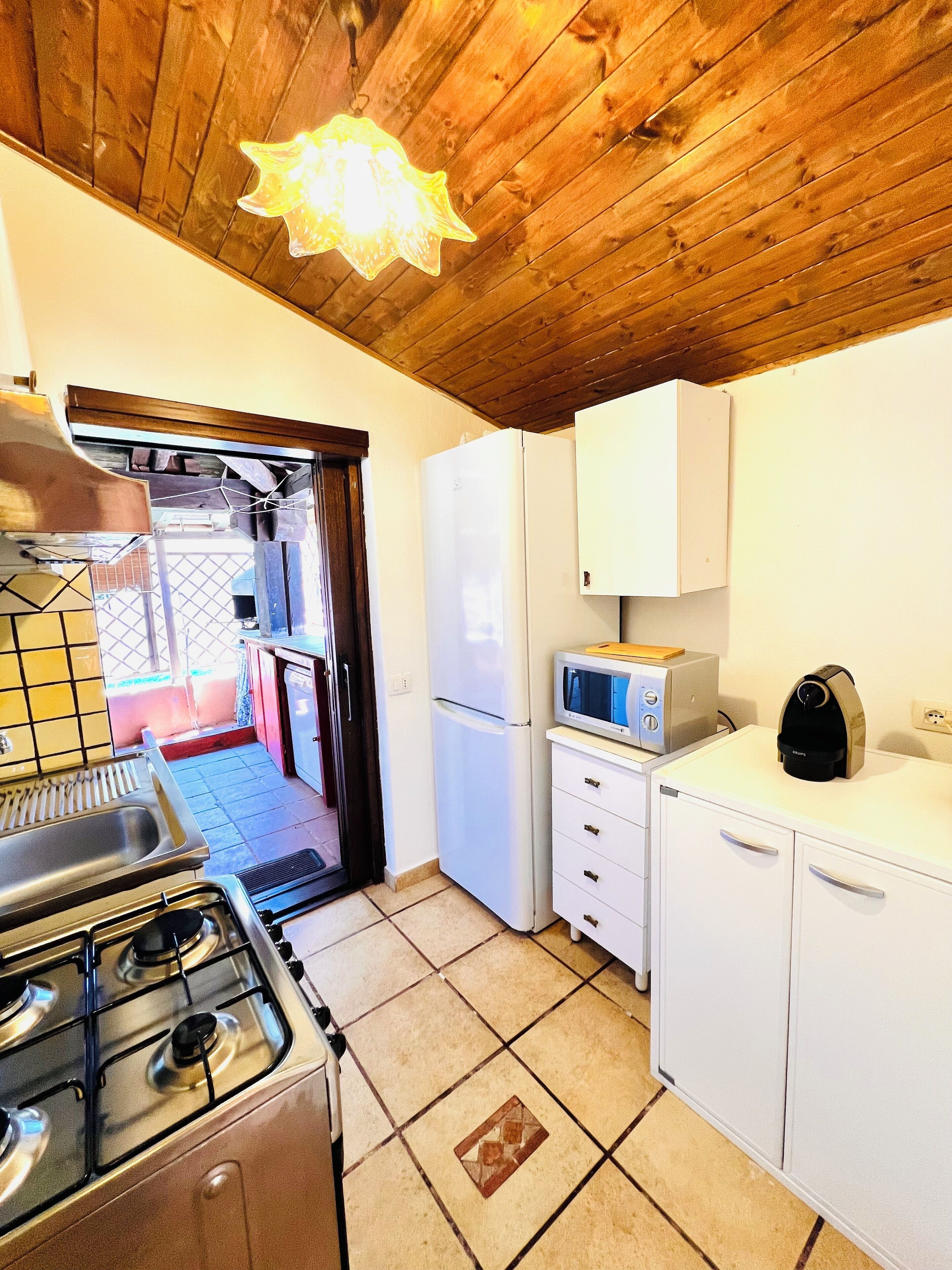 A compact kitchen with a gas stove, white cabinets, a microwave, and a refrigerator.