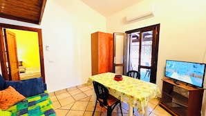 A small, cozy room with a bed, a dining table, and a TV. - Bilocale Lu Liciu H10 in Centro (San Teodoro)