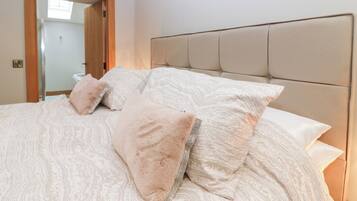 Un dormitorio con cama, cabecera y puerta que da a un baño.