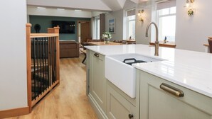 A spacious kitchen with a large island, wooden flooring, and pendant lighting. - The Old Kipper Hoose (Banff)
