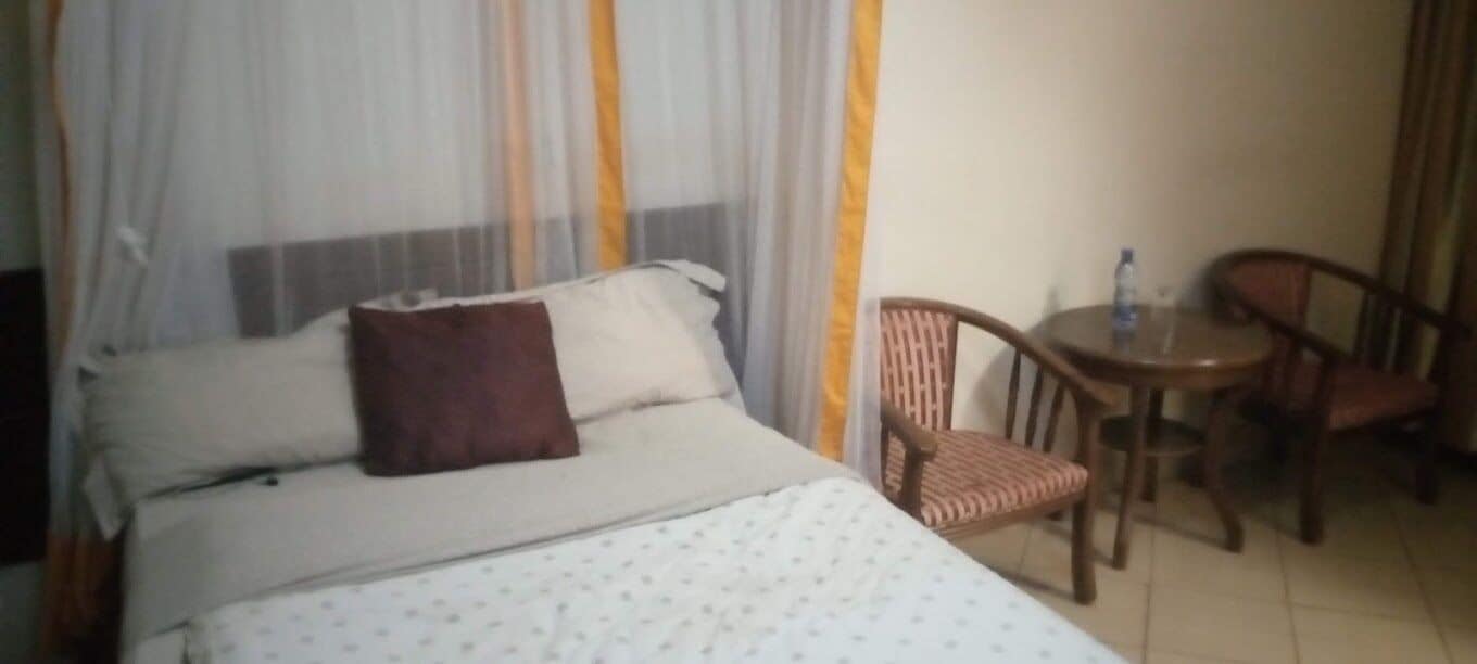 A hotel room with a bed, a chair, and a small table.
