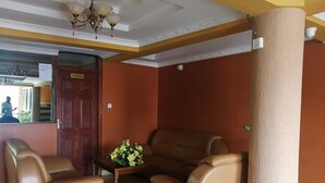 A room with two leather sofas, a wooden coffee table with flowers, a chandelier, and a wooden door.