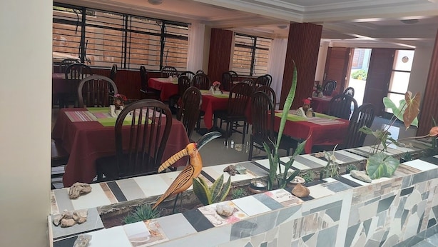 A restaurant with multiple tables and chairs, a decorative bird sculpture, and a tiled counter.