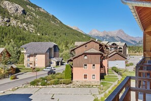 A mountain resort with wooden buildings, a parking area, and a view of the mountains. - Residence Odalys Aquisana (La Salle-les-Alpes)