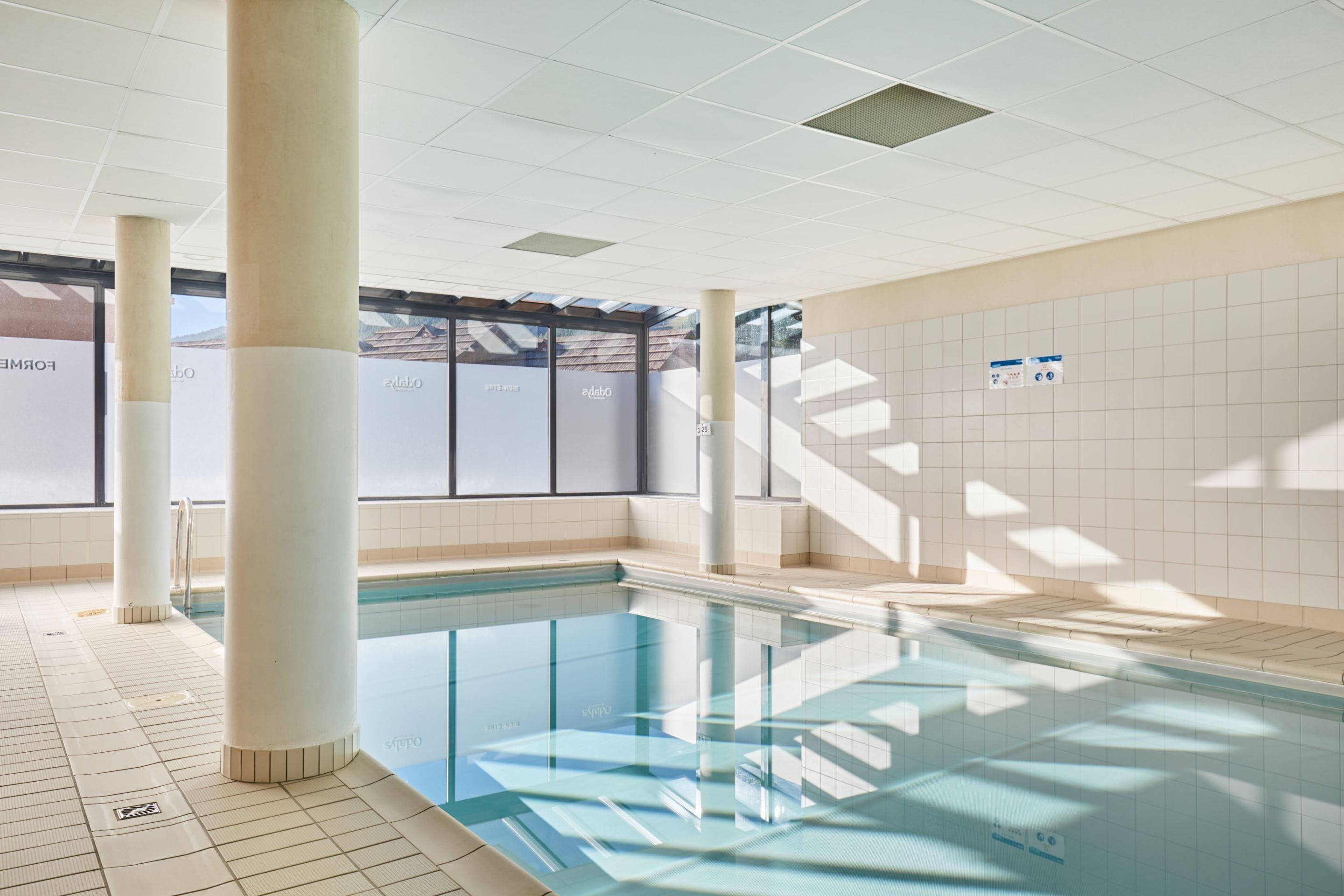 Zwembad met betegelde wanden en een plafond met inbouwverlichting.