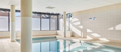 A swimming pool with tiled walls and a ceiling with recessed lighting.