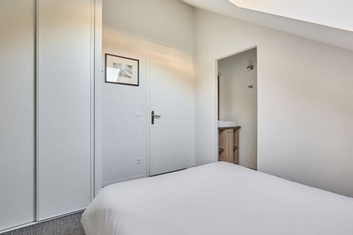 A hotel room with a bed, a wardrobe, and a bathroom visible through an open door.