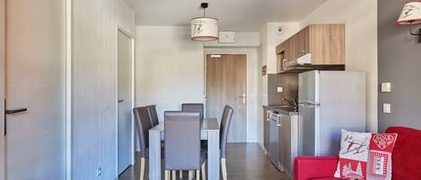 Cozinha moderna com forno embutido, área de jantar com mesa e cadeiras, e um sofá vermelho com almofada decorativa.