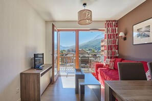 A modern living room with a red sofa, a wooden coffee table, and a television on a wooden stand.