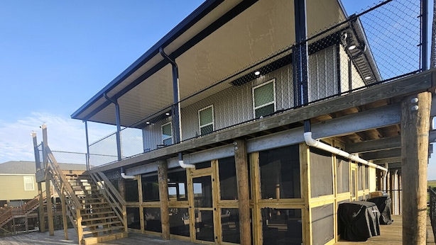 A wooden deck with a covered seating area and a staircase leading to a balcony. - Delacroix- Hopedale Lodge and Fishing Charters.  South Louisiana sportsman`s paradise premier lodging and fishing adventure (Hopedale)