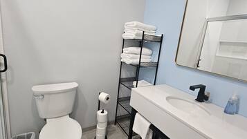A bathroom with a toilet, a sink, a towel rack, and a mirror.