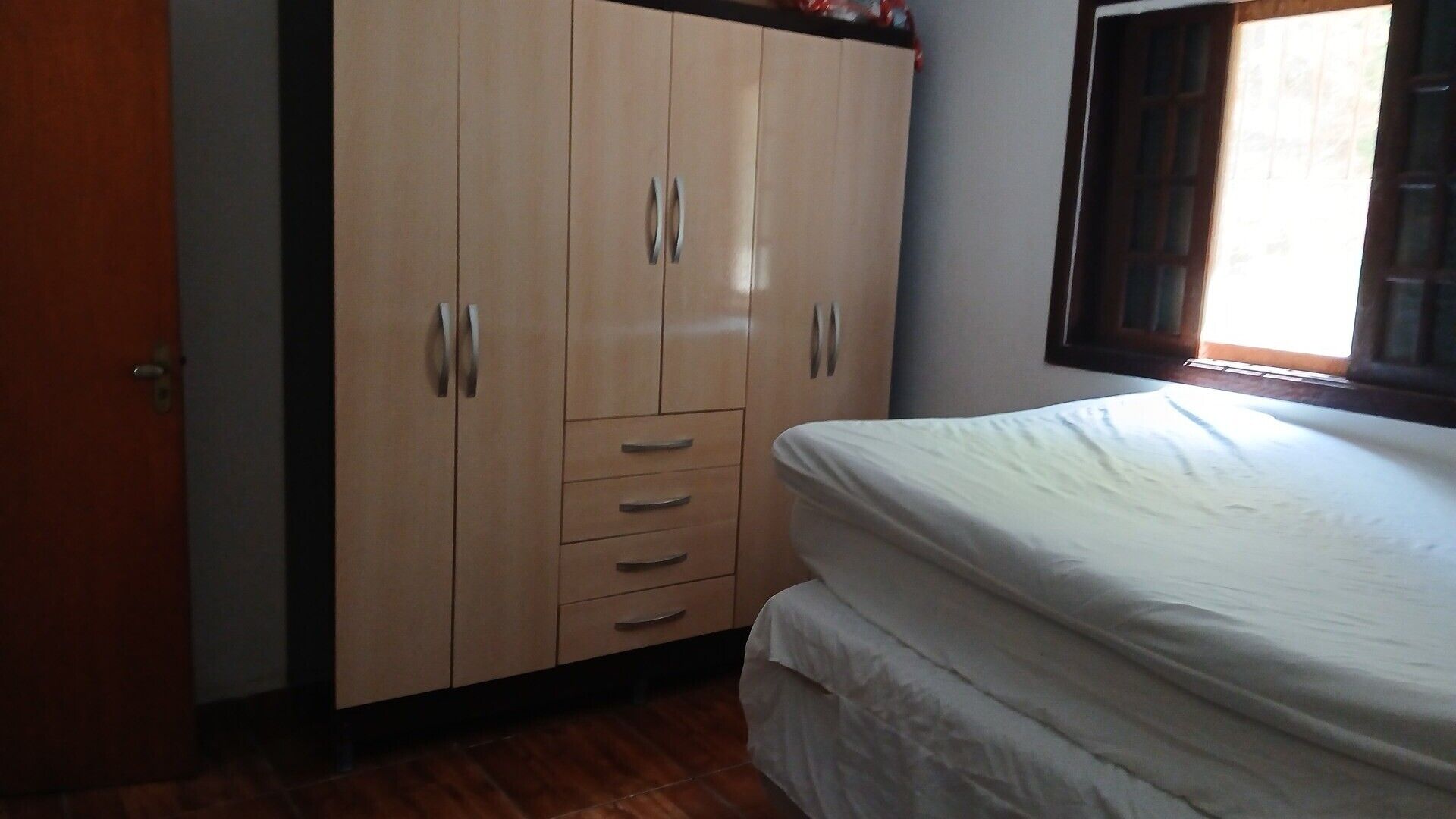 Un dormitorio con cama, armario y ventana.