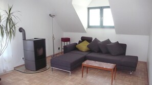 A modern living room with a sectional sofa, a small table, a floor lamp, and a built-in heater.