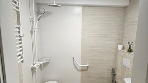 A modern bathroom with a shower, toilet, and sink.