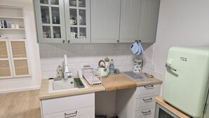 A compact kitchen with a sink, countertop, cabinets, and a vintage refrigerator.