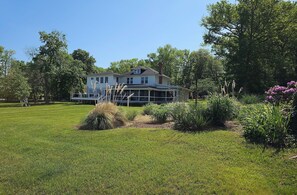 A two-story house with a covered porch, surrounded by a well-maintained lawn and various plants. - Breathtaking Sunset-4 bedroom house in Aberdeen (Aberdeen)
