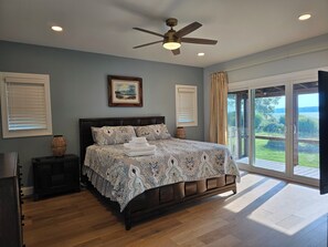 A bedroom with a large bed, a ceiling fan, and a view of a garden through a sliding glass door. - Breathtaking Sunset-4 bedroom house in Aberdeen (Aberdeen)