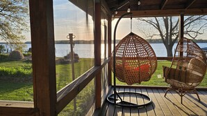 Una terrazza in legno con poltrone a dondolo che si affaccia su un lago.