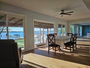 A spacious dining area with a view of a lake and dock, wooden flooring, and a ceiling fan. - Breathtaking Sunset-4 bedroom house in Aberdeen (Aberdeen)