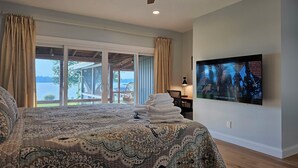 Una camera da letto con un letto grande, un ventilatore a soffitto, una TV e vista sull'esterno.