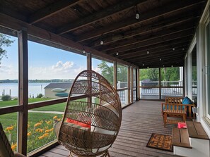 A covered porch with a wicker chair, wooden deck, and a view of a lake. - Breathtaking Sunset-4 bedroom house in Aberdeen (Aberdeen)