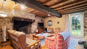 Una sala de estar acogedora con chimenea de piedra, muebles de madera y un ventanal grande.