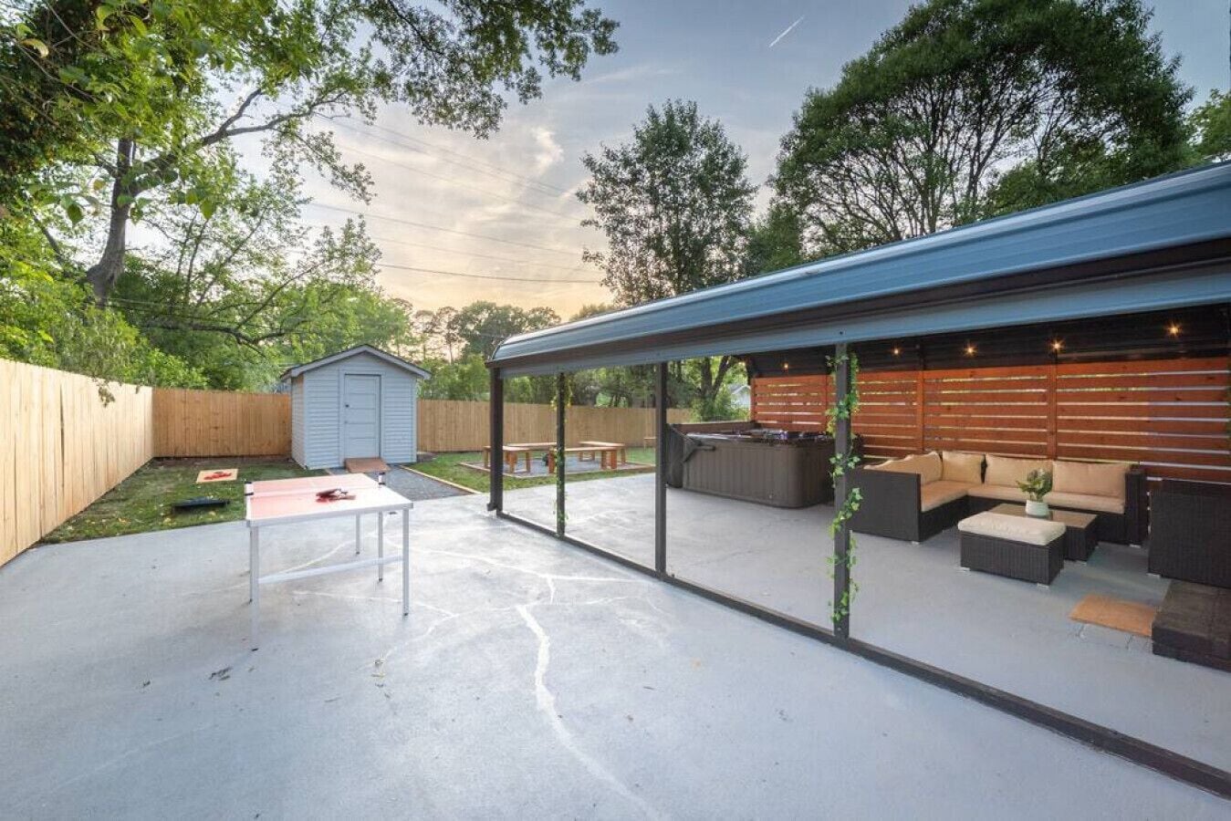 A covered patio area with outdoor seating, a hot tub, and a small shed.