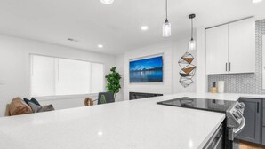 Una cocina moderna con una isla grande, armarios blancos y vista a un lago a través de la ventana.