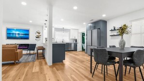 Un apartamento moderno con sala de estar, comedor, cocina y un televisor grande.