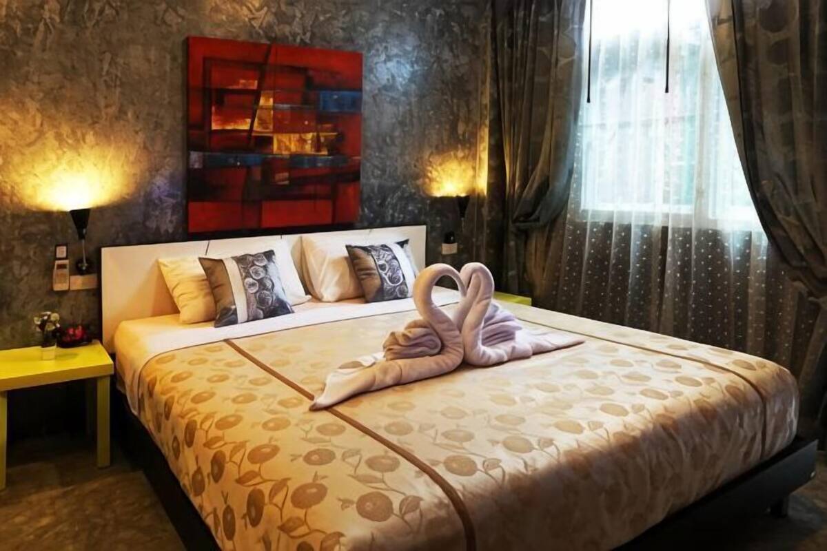 A hotel room with a large bed, two bedside tables, a wall-mounted shelf, and a window with curtains.