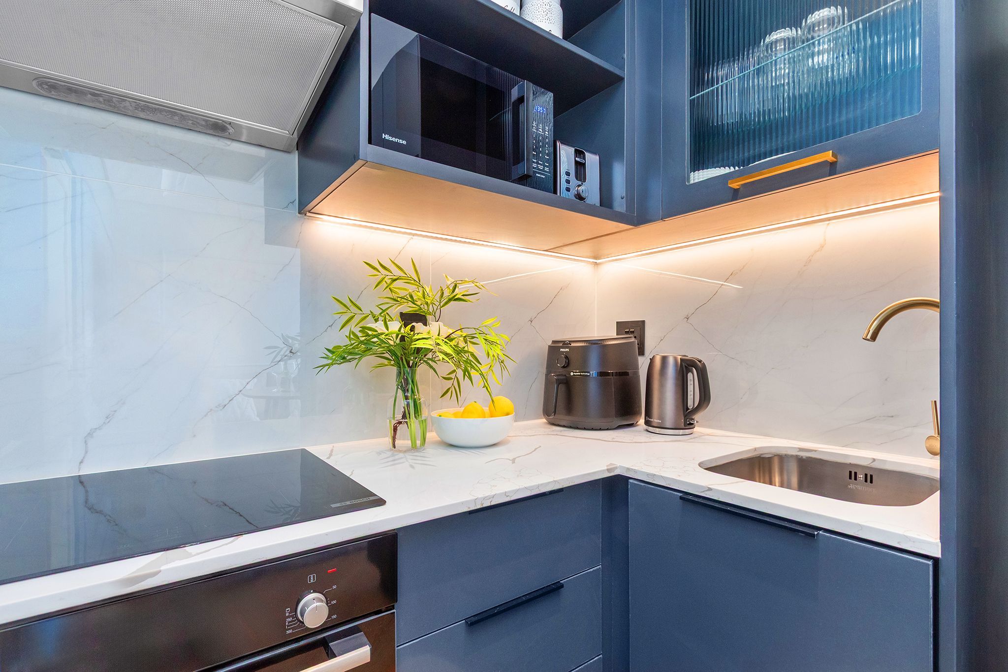 A modern kitchen with a black induction cooktop, a built-in coffee maker, and a stainless steel sink.