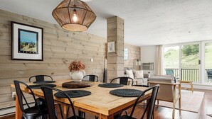 Un coin repas avec une table et des chaises en bois, un luminaire suspendu et un tableau encadré au mur.