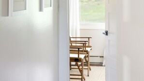 Un couloir orné de tableaux encadrés, une chaise en bois et, au fond, une vue sur une pièce par une porte ouverte.