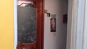 Uma porta de madeira com painel de vidro fosco, uma parede branca com uma pequena moldura e uma parede texturizada branca à direita.