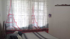 Quarto com cama, mesa de cabeceira e janela com vista para a Torre Eiffel.
