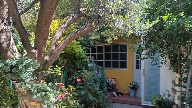 Um caminho de pedra estreito que leva a um edifício amarelo com uma janela e uma porta.