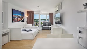 A modern hotel room with a bed, a desk, a sofa, and a TV. - Studio in Ozone Condo in Kata A702 (Karon)